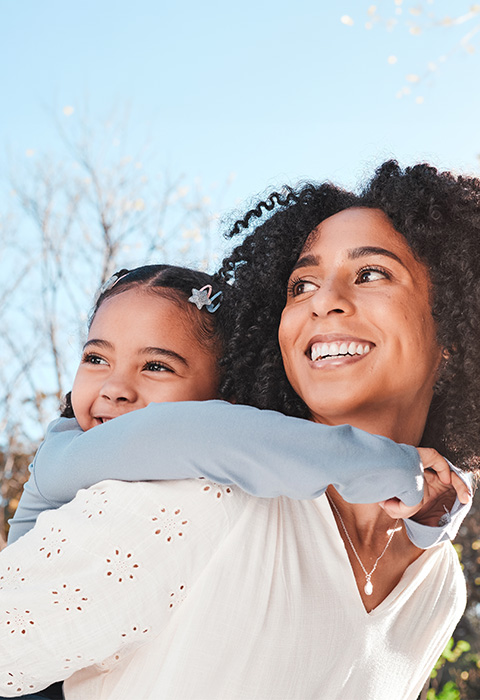 Mère avec sa fille sur le dos pour illustrer l'assurance-placement en branche 23 de DVV 