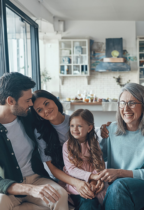 Grands-parents, parents et enfant dans le canapé pour illustrer la page des épargne-pensions de DVV