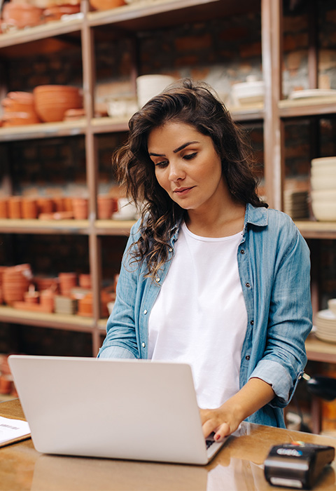 Vrouw werkt op laptop in haar keramiekwinkel als illustratie voor de pagina pensioensparen voor zelfstandigen van DVV 