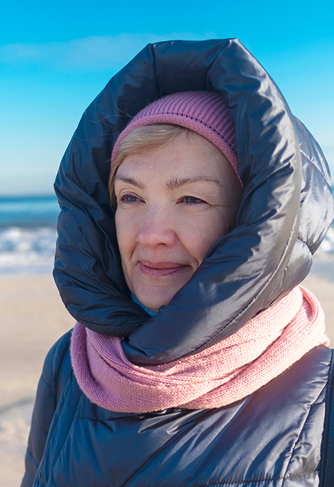 Goed ingeduffelde denkende vrouw aan de Noordzee als illustratie voor de vergelijkingspagina van pensioenproducten van DVV 