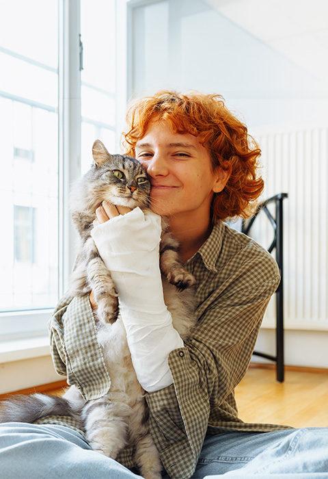 Meisje met gebroken arm knuffelt kat als illustratie voor de pagina van de verzekering ongeval privéleven van DVV