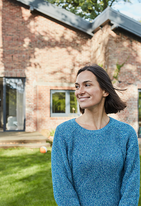 Vrouw staat buiten voor een nieuwbouwhuis als illustratie voor de pagina hypothecair krediet bij DVV