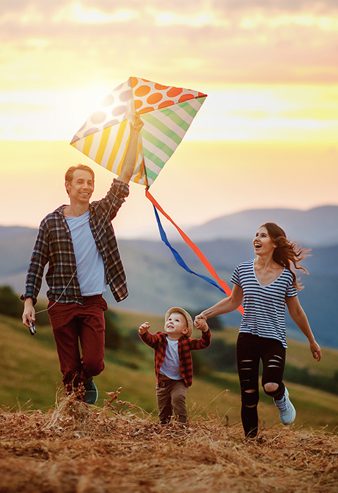 Famille en montagne avec un cerf-volant pour illustrer la page de l'assurance et l'assistance voyage chez DVV