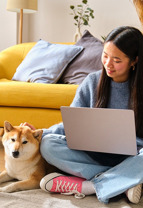 Meisje op de grond voor haar zetel met laptop als illustratie voor de pagina optie media van de woningverzekering van DVV 