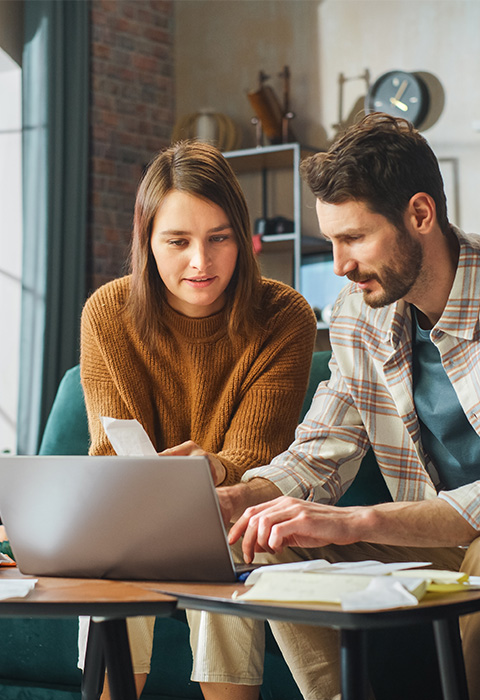 Een koppel raadpleegt documenten op laptop als illustratie van de optie onrechtstreekse verliezen van  de woningverzekering