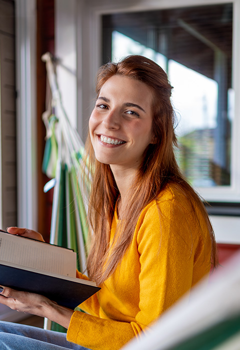 Jeune femme souriante tenant une tablette pour illustrer la page de l'assurance habitation Cocoon Start de DVV