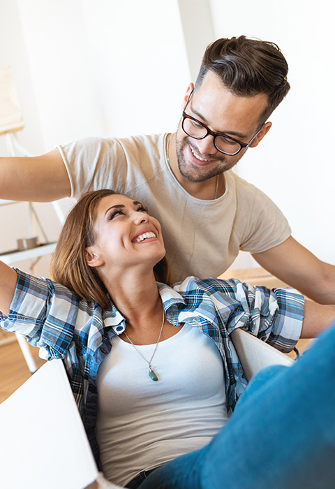 Jeune couple dans les cartons de déménagement pour illustrer la page de l'assurance habitation pour propriétaires de DVV