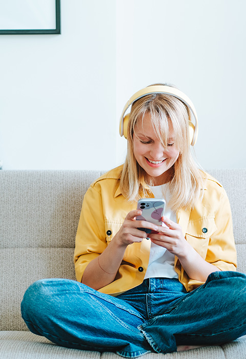 Jeune femme sur le canapé avec son smartphone pour illustrer la page de l'assurance locataire de DVV