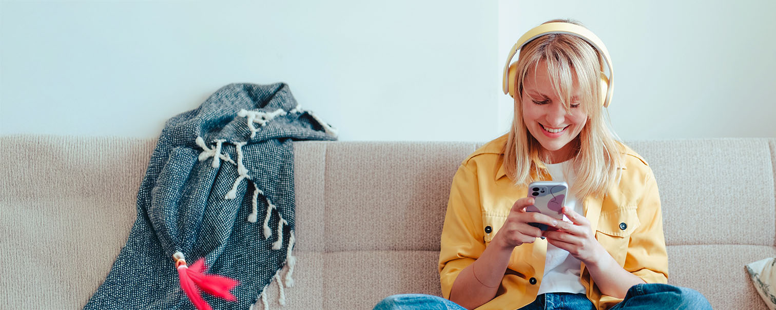 Jong meisje op de bank met haar smartphone als illustratie voor de pagina van woningverzekeringen voor huurders van DVV 