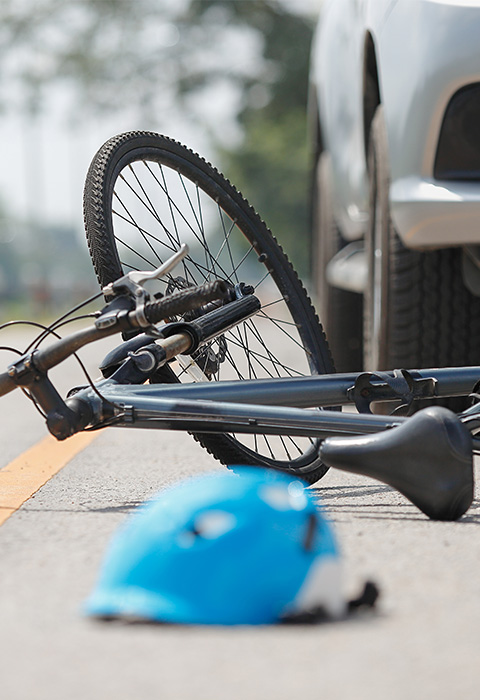 Accident de voiture avec un vélo et un casque au sol pour illustrer la page de l'assurance Accidents Circulation de DVV