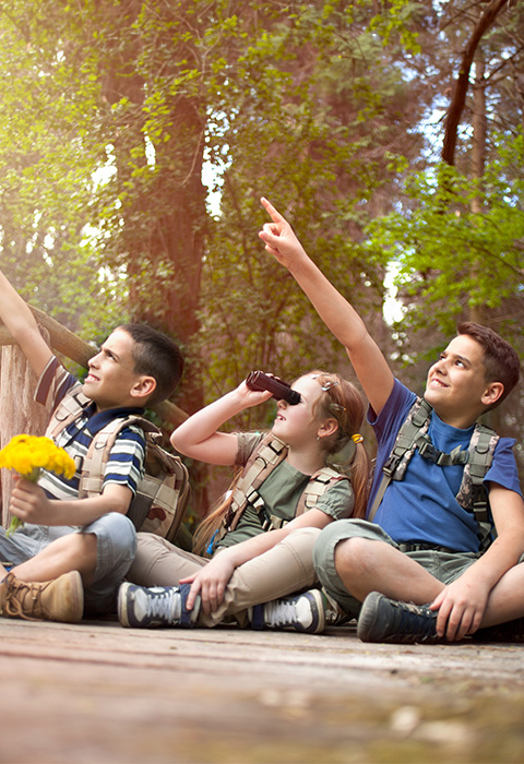 Trois enfants jouant dans les bois (mouvement de jeunesse) pour illustrer l'assurance pour les ASBL et les associations de DVV