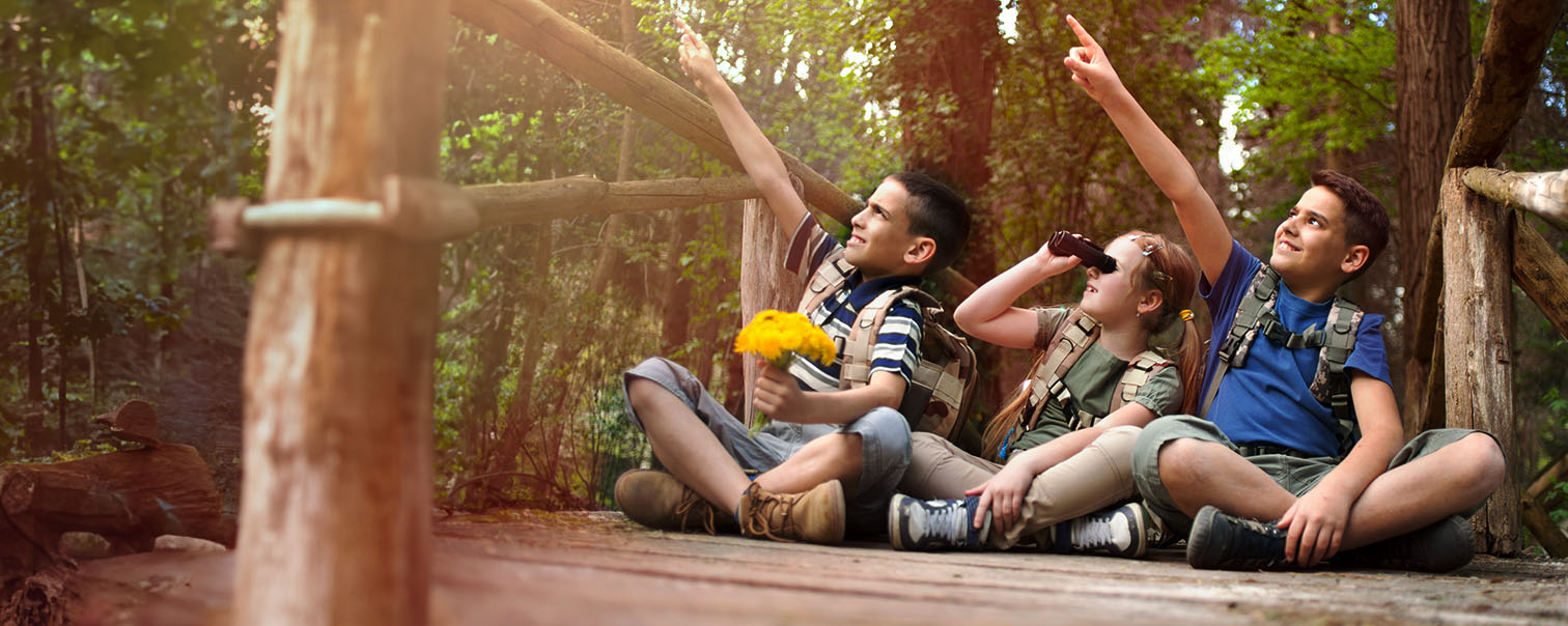 Trois enfants jouant dans les bois (mouvement de jeunesse) pour illustrer l'assurance pour les ASBL et les associations de DVV