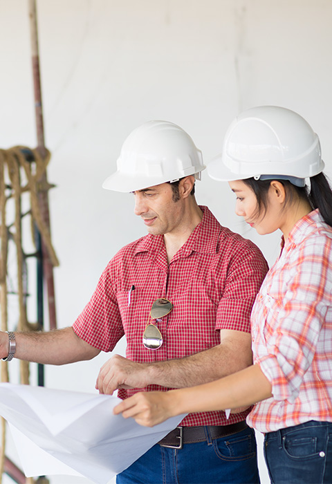 Deux personnes regardant les plans sur un chantier de construction pour illustrer l'assurance Tous risques chantier de DVV