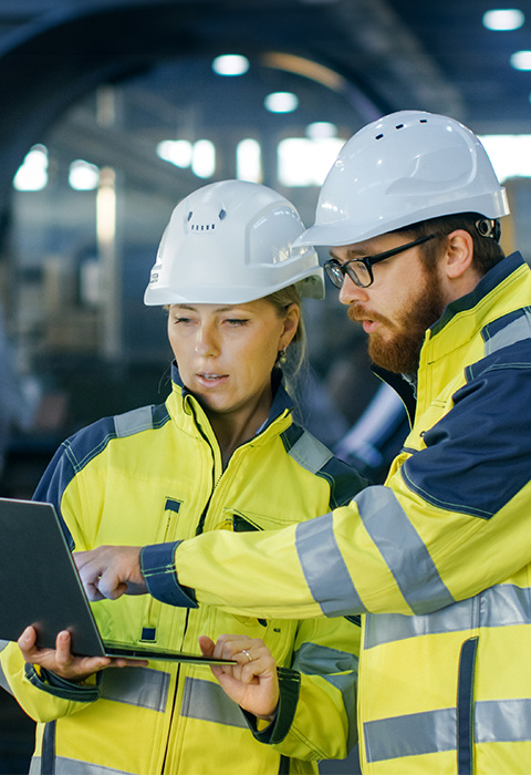Twee personen gekleed in werfoutfit als illustratie voor de pagina van verzekeringen van gebouwen en machines 