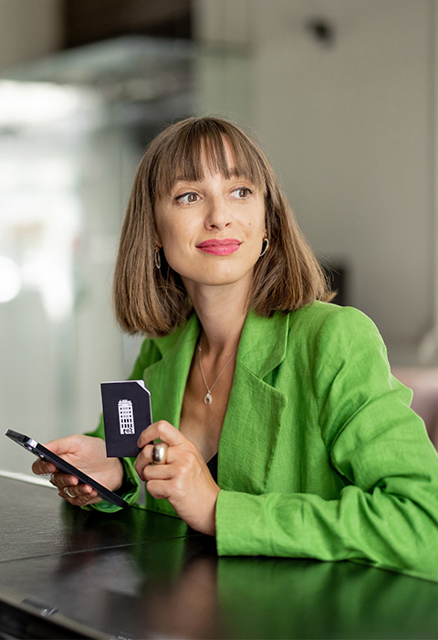 Femme pensive attendant son café dans un établissement pour illustrer la page des assurances Pension et Protection pour indépendants