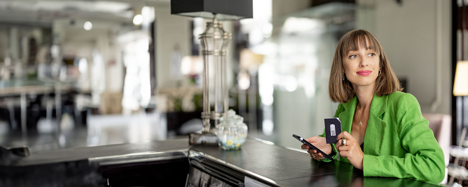 Femme pensive attendant son café dans un établissement pour illustrer la page des assurances Pension et Protection pour indépendants